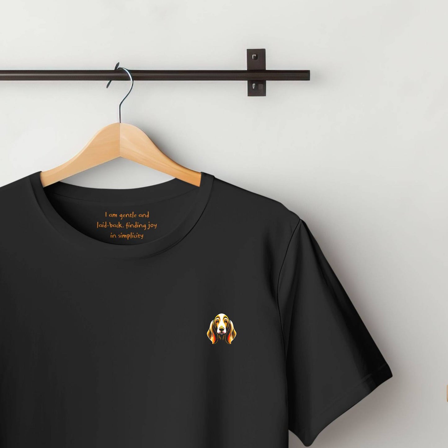 100% Organic Cotton Black t-shirt featuring a super-large bold, colourful graphic on the chest of a Basset Hound. Inside the collar, the text reads " I am gentle and laid-back, finding joy in simplicity'